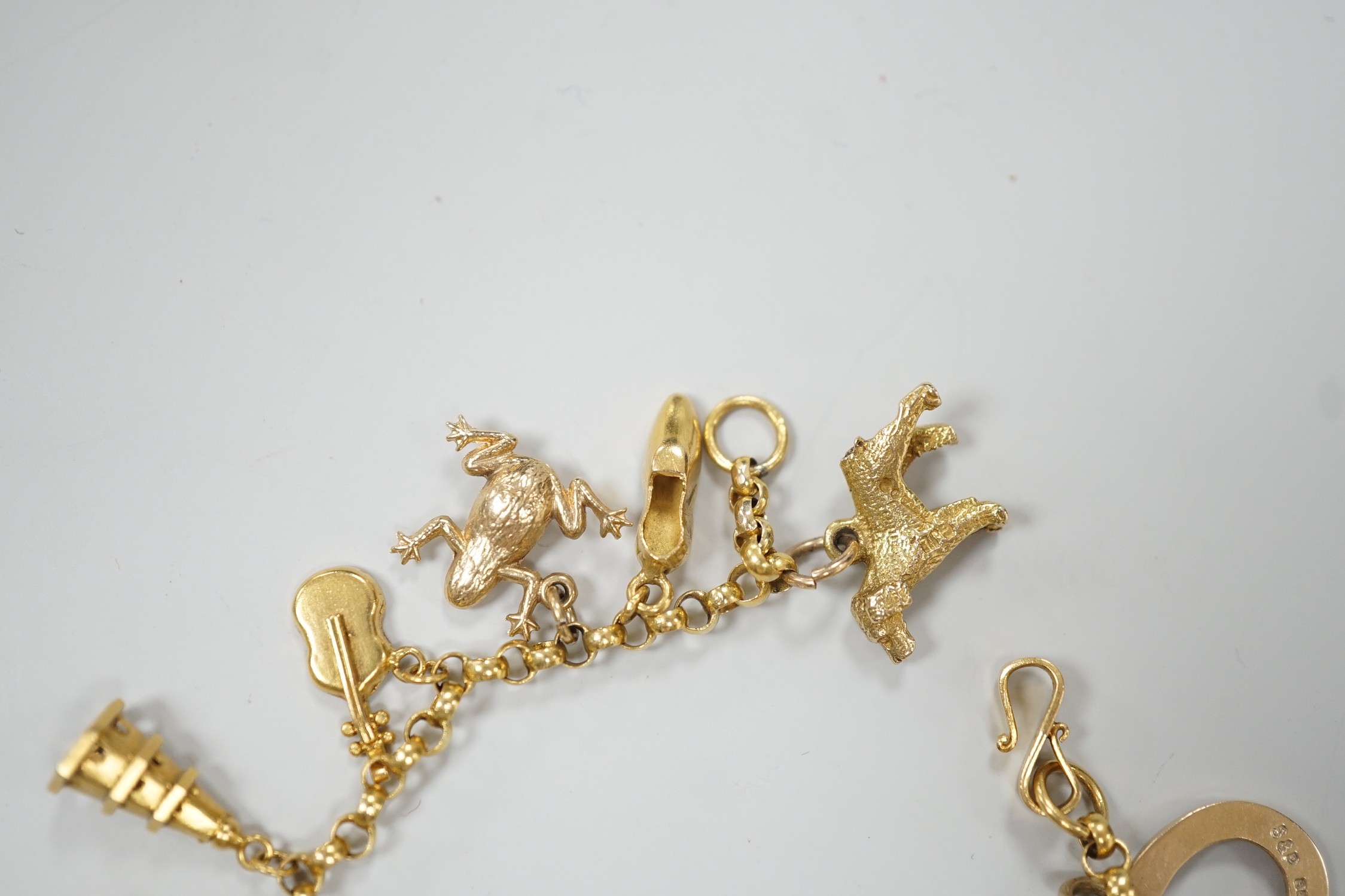 A Chinese yellow metal charm bracelet, hung with thirteen assorted yellow metal charms including four 9ct, 15.5cm